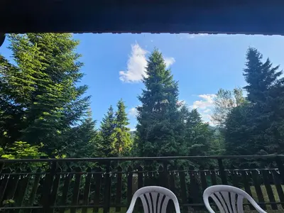 two white chairs sitting on a balcony with trees at willa Partykówka in Poręba Wielka