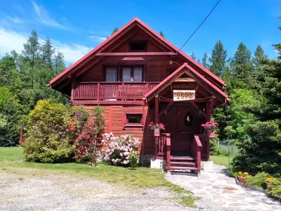 a log cabin with a balcony and flowers in front of it at Dom Gościnny E-Lufka in Zawoja