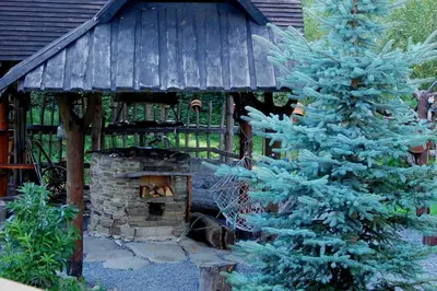 a building with a stone oven next to a pine tree at Dom Gościnny E-Lufka in Zawoja