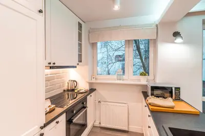 a kitchen with white cabinets and a window at Heart of Kraków Comfort Apartments by Rentujemy in Kraków