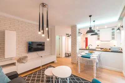 a kitchen and a living room with a table and chairs at Heart of Kraków Comfort Apartments by Rentujemy in Kraków