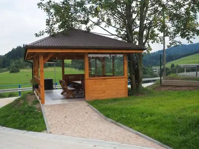 a wooden gazebo with a picnic table in the grass at Folwark Bielanka in Bielanka