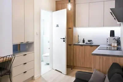 a kitchen with white cabinets and a door leading to a sink at Cozy Studio for couples - Cracow city heart in Kraków