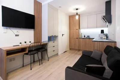 a living room with a couch and a kitchen at Cozy Studio for couples - Cracow city heart in Kraków