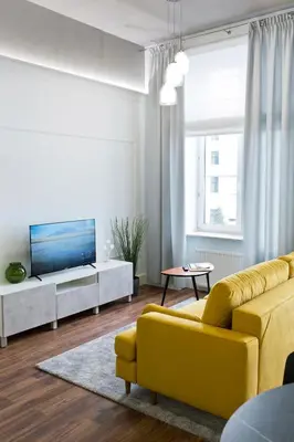 a living room with a yellow couch and a tv at Charming 2-Room Apartment Near Wawel Castle in Kraków