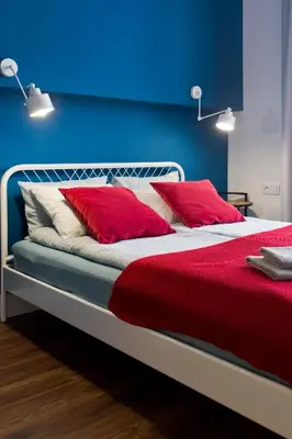 a bed with red and white pillows and a blue wall at Charming 2-Room Apartment Near Wawel Castle in Kraków