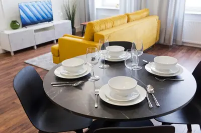 a black table with plates and glasses and a yellow couch at Charming 2-Room Apartment Near Wawel Castle in Kraków