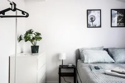 a white bedroom with a bed and a plant on a dresser at Fully-furnished Apartment with Air Conditioning for families, Cracow Old Town in Kraków