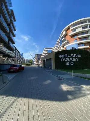 a street in front of a building with a sign at Beautiful Apartment- FREE GARAGE- WIŚLANE TARASY in Kraków
