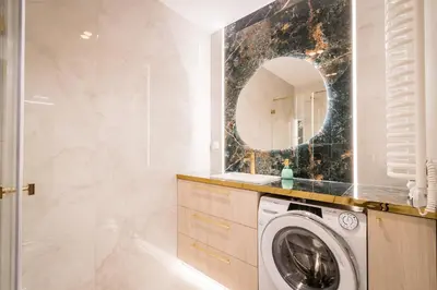 a bathroom with a washing machine and a mirror at Greendustry Zabłocie Luxury Apartments WAWELOFTS in Kraków