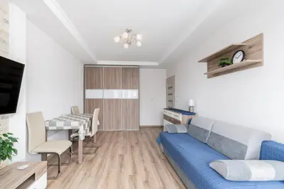 a living room with a blue couch and a table at Park Białoprądnicki Blue Studio by BookingHost in Kraków