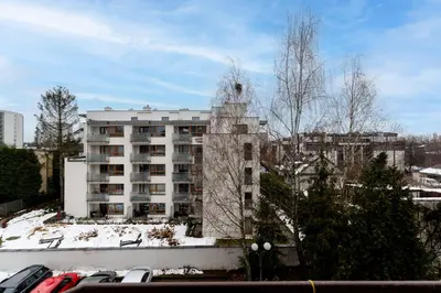 a tall white building in front of a building at Park Białoprądnicki Blue Studio by BookingHost in Kraków