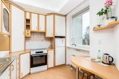 a kitchen with white cabinets and a wooden table at Park Białoprądnicki Blue Studio by BookingHost in Kraków