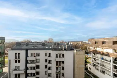 a white building with a black roof in a city at Lea Cosy Apartment by BookingHost in Kraków