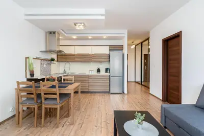 an open kitchen and living room with a blue couch at Lea Cosy Apartment by BookingHost in Kraków