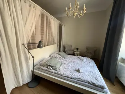a bedroom with a bed with a chandelier and a window at Apartament rodzinny 14 in Kraków