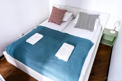 a white bed with blue sheets and pillows at Center High Apartment CityBeat#1 in Kraków