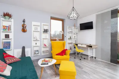 a living room with yellow chairs and a desk at Apartments Cracow Czeczow by Noclegi Renters in Kraków