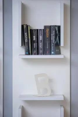 a book shelf with books and a letter on it at Apartments Cracow Czeczow by Noclegi Renters in Kraków