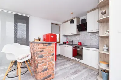 a kitchen with white cabinets and a brick wall at Apartments Cracow Czeczow by Noclegi Renters in Kraków