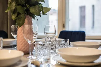 a table with plates and glasses and a vase with a plant at CracWoW K8 No.6 Apartment in Kraków