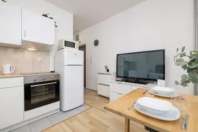 a white kitchen with a table and a tv at Pet-Friendly & Cozy Studio in Kraków by Noclegi Renters in Kraków