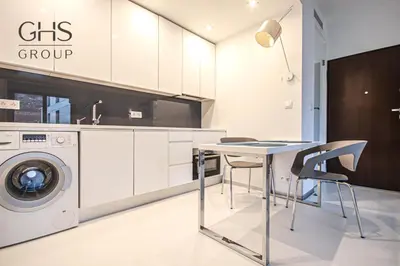 a kitchen with a table and a washing machine at Ekskluzywny Apartament obok Zamku Wawelskiego in Kraków