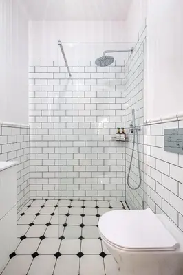 a white tiled bathroom with a toilet and a shower at Discover Krakow Apartments - Lubomirskiego St - Classic & Modern - Near Main Station, Netflix and AC in Kraków
