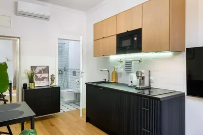 a kitchen with a black counter top and a bathroom at Discover Krakow Apartments - Lubomirskiego St - Classic & Modern - Near Main Station, Netflix and AC in Kraków