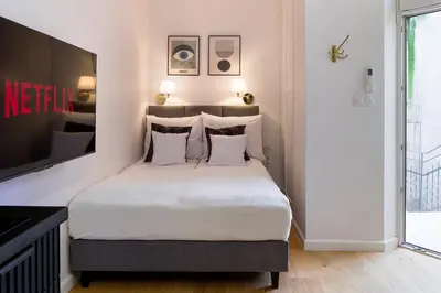 a bedroom with a bed with white sheets and a tv at Discover Krakow Apartments - Lubomirskiego St - Classic & Modern - Near Main Station, Netflix and AC in Kraków