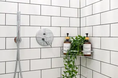 a white tiled bathroom with two bottles of wine at Discover Krakow Apartments - Lubomirskiego St - Classic & Modern - Near Main Station, Netflix and AC in Kraków