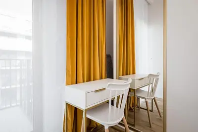 a dining room with white tables and chairs and yellow curtains at Golden residence apartment in Kraków