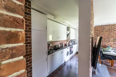 a kitchen with white cabinets and a brick wall at LARGE LUXURY APARTMENT WIELICZKA in Wieliczka