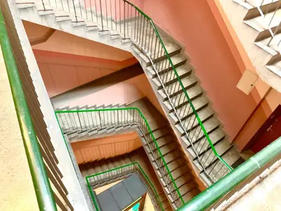 a spiral staircase in a building with a green railing at Apartament S19 in Kraków
