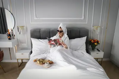 a woman sitting on a bed reading a book at Paris in Cracow Apartment in Kraków