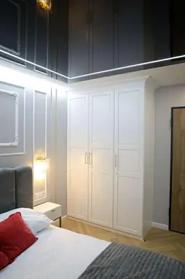 a bedroom with white cabinets and a bed with a red pillow at Paris in Cracow Apartment in Kraków