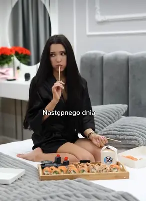 a woman sitting on a bed with a tray of food at Paris in Cracow Apartment in Kraków