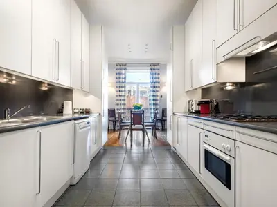 a kitchen with white cabinets and a table with chairs at Tyzenhauz Apartments Podwale street in Kraków