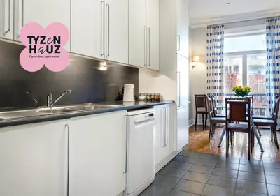 a kitchen with white cabinets and a dining room at Tyzenhauz Apartments Podwale street in Kraków