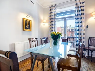 a dining room with a table and chairs and a window at Tyzenhauz Apartments Podwale street in Kraków