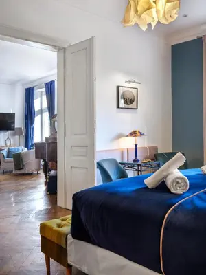 a bedroom with a blue bed and a living room at Tyzenhauz Apartments Podwale street in Kraków