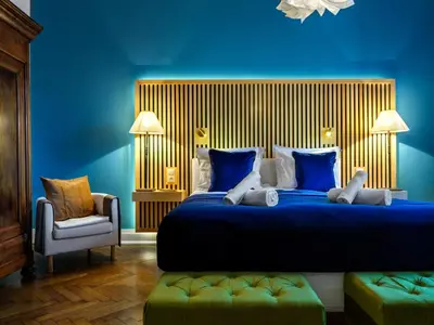 a blue bedroom with a large bed and a chair at Tyzenhauz Apartments Podwale street in Kraków
