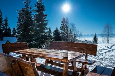 a wooden picnic table in the snow with a cup on it at Jankówki - Dom w górach in Nowy Targ