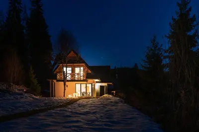 a house lit up at night in the snow at Jankówki - Dom w górach in Nowy Targ