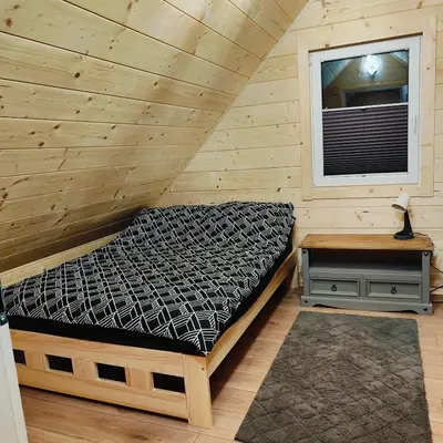 a bed in a wooden room with a window at beskid.house1 in Spytkowice