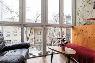 a living room with a couch and a table and windows at Luminous Loft - Modern Old Town Apartment - by Upstairs in Kraków