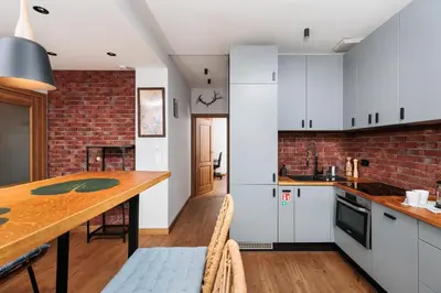 a kitchen with white cabinets and a brick wall at Luminous Loft - Modern Old Town Apartment - by Upstairs in Kraków
