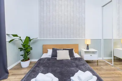 a bedroom with a large bed and a plant at Nowoczesny apartament w ścisłym centrum Krakowa - by Upstairs in Kraków