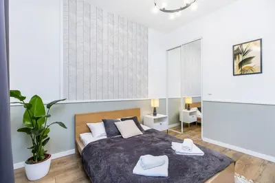 a bedroom with a bed and a potted plant at Nowoczesny apartament w ścisłym centrum Krakowa - by Upstairs in Kraków
