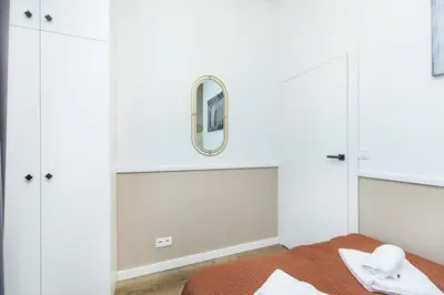 a bedroom with white cabinets and a mirror at Nowoczesny apartament w ścisłym centrum Krakowa - by Upstairs in Kraków
